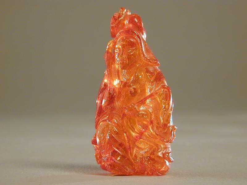 Amber Figurine of a Seated Deity with a Whisk and Lotus