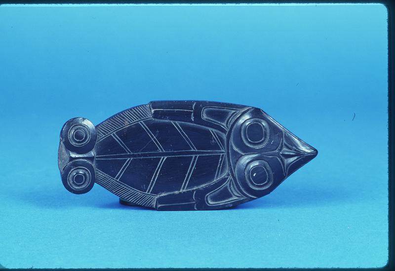 Carving in the shape of a Flat Fish with a creature depicted on the top